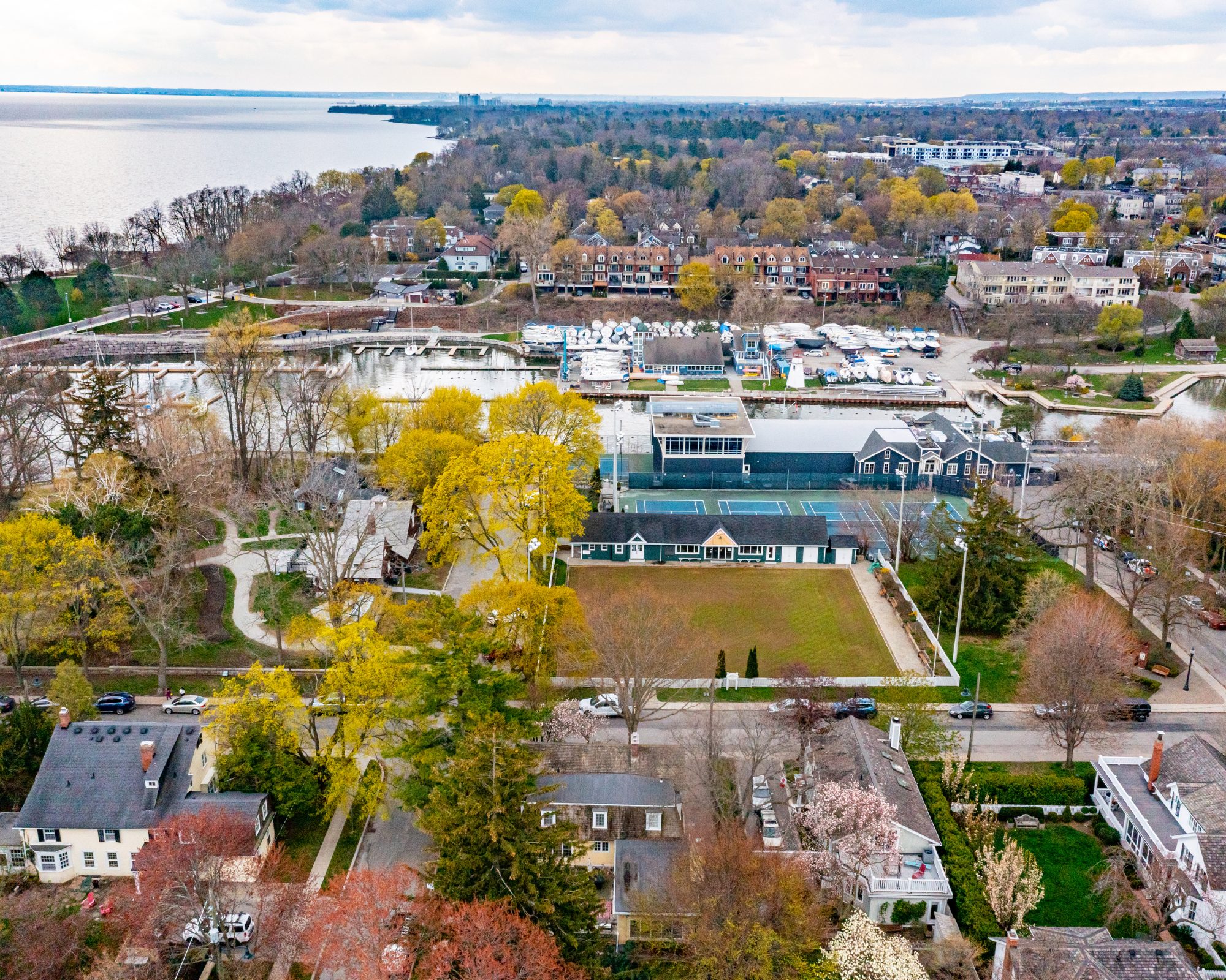 Aerial view of Oakville Club with boats, tennis courts, nearby homes, and surrounding park